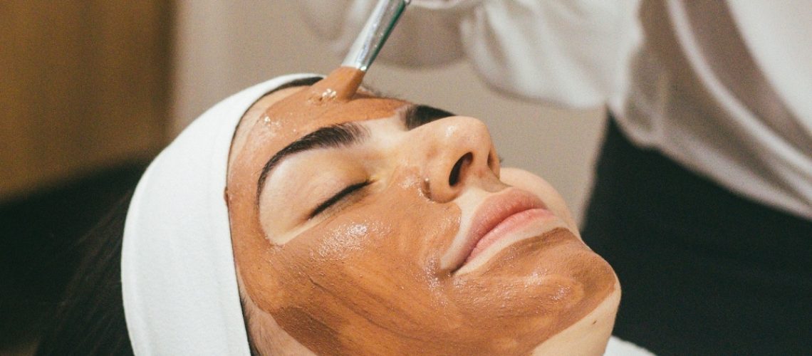 Beauty therapist applying face mask to woman