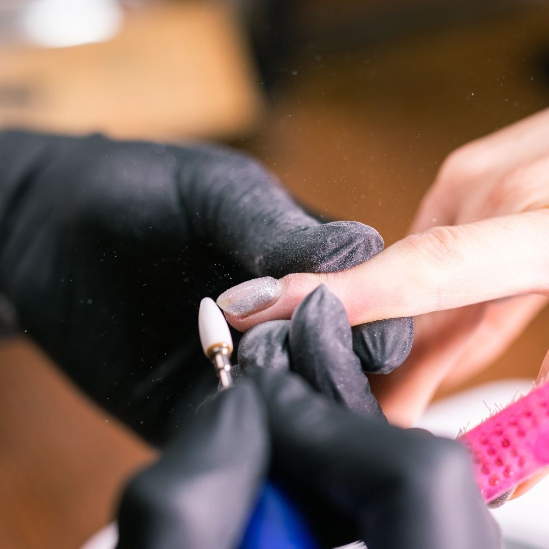 Nail tech making adjustments to a nail